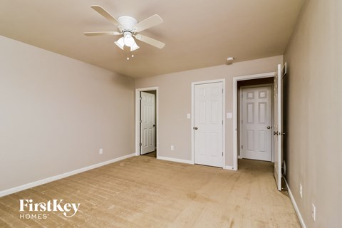a living room with a ceiling fan and a door into a hallway