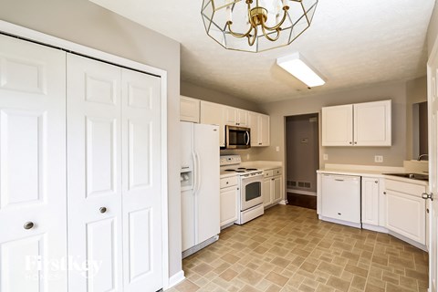a kitchen with white cabinets and appliances and a chandelier