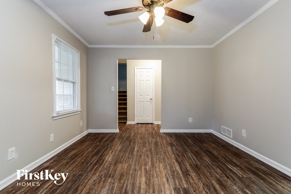 an empty living room with a ceiling fan and wood flooring