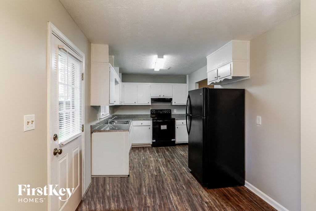 a kitchen with white cabinets and a black refrigerator