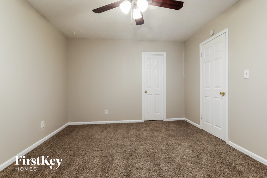 an empty room with carpet and a ceiling fan