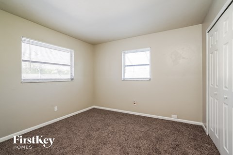 a bedroom with carpet and two windows and a door