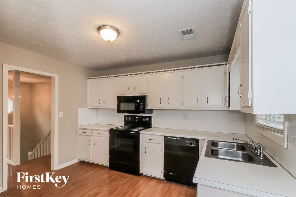 a kitchen with white cabinets and black appliances