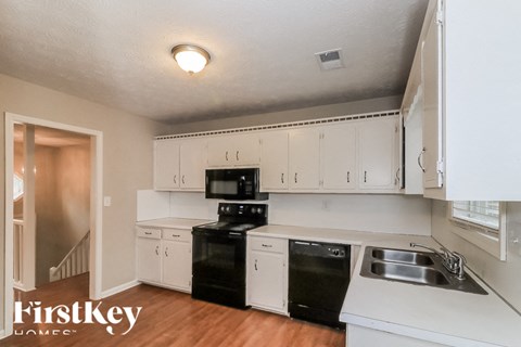 A kitchen with white cabinets and black appliances.