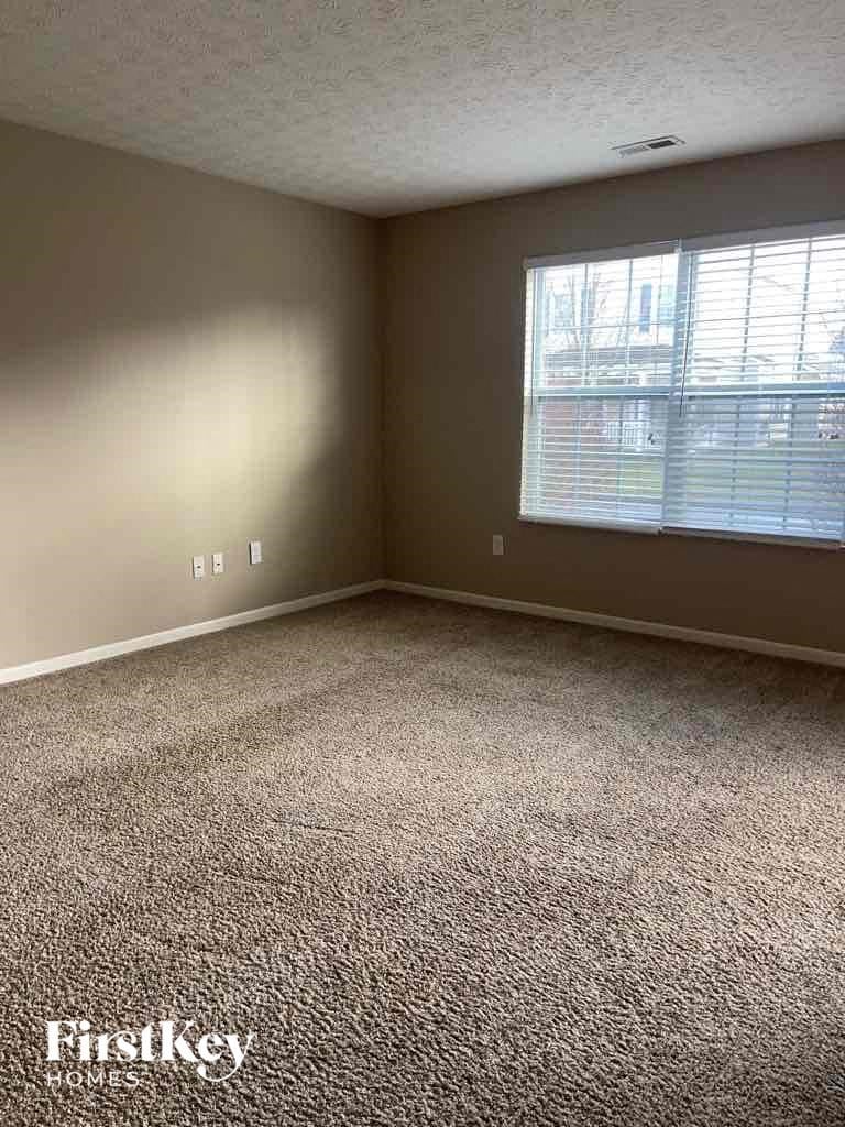 A room with a carpeted floor and a window with blinds.