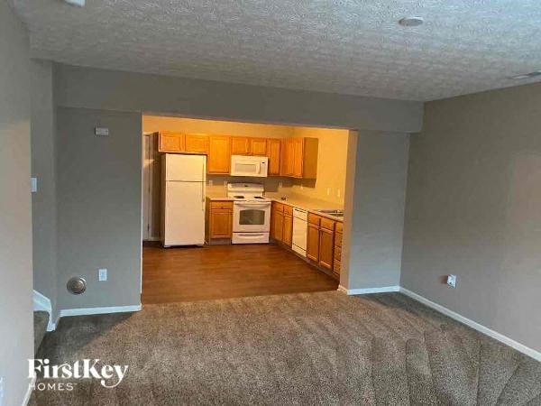 A kitchen with white appliances and wooden cabinets.