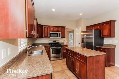 A kitchen with brown cabinets and a granite countertop.