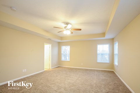a spacious living room with carpet and a ceiling fan