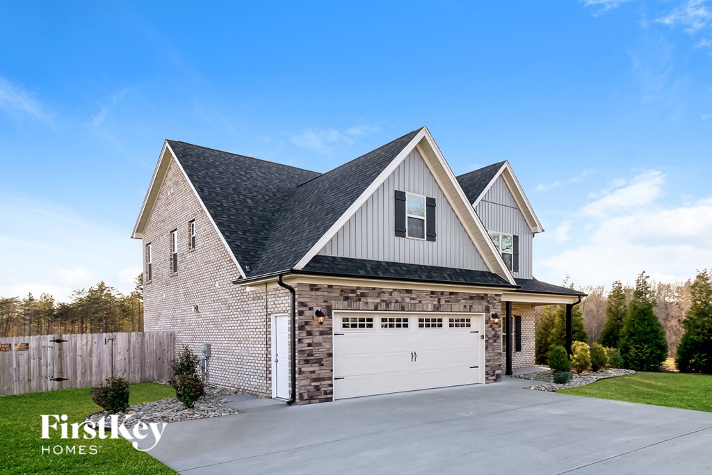a brick house with a white garage door in front of a driveway