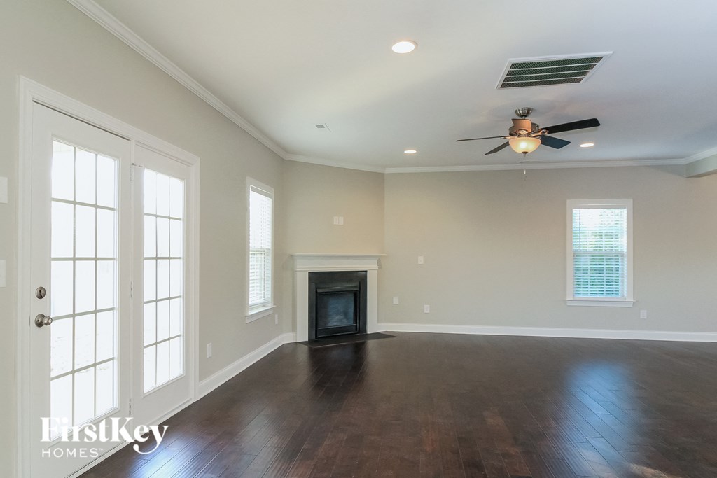 an empty living room with a ceiling fan and a fireplace