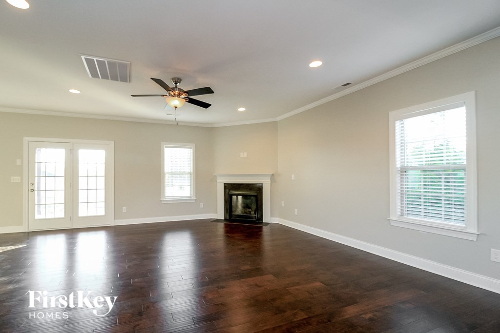an empty living room with a ceiling fan and a fireplace