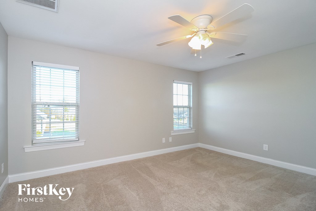 a bedroom with a ceiling fan and two windows