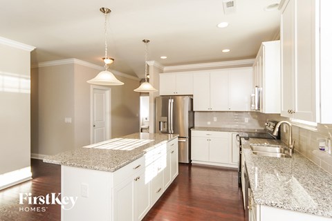 a white kitchen with granite counter tops and white cabinets