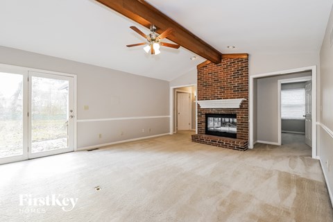 A spacious living room with a fireplace and a ceiling fan.