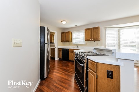 A kitchen with wooden cabinets and a black fridge.