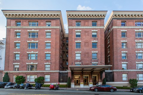 A red brick building with a black car parked in front.