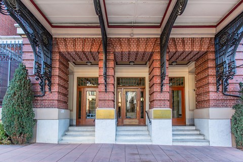 The front of a building with a red brick wall and a black iron gate.