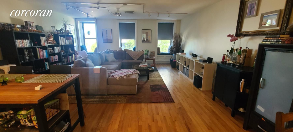 A living room with a couch, a chair, a table, a bookshelf, and a television.
