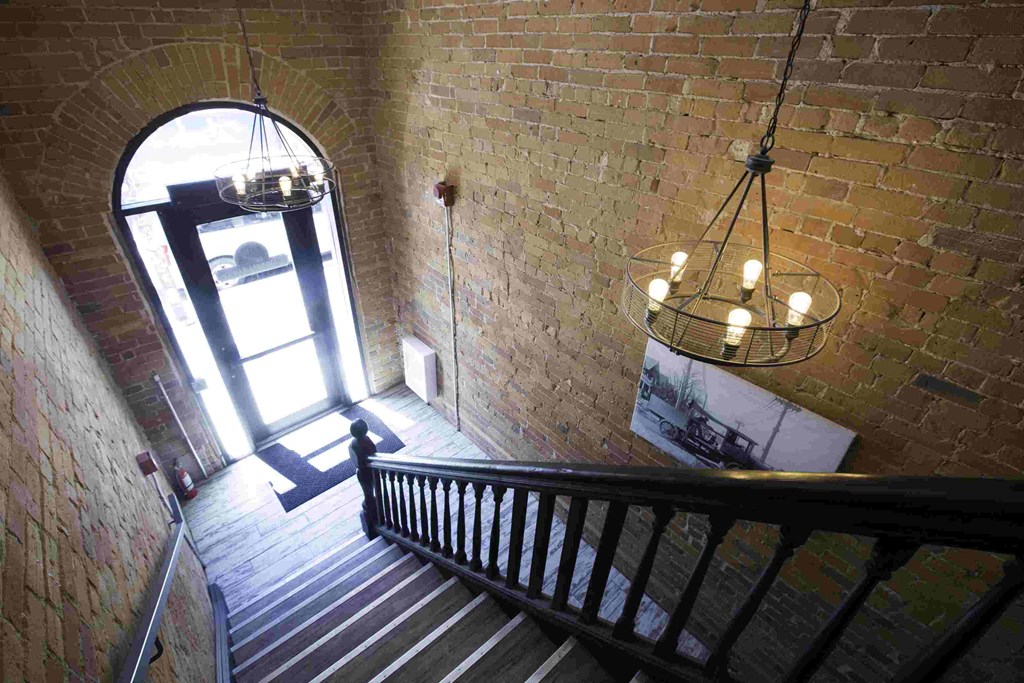 the stairway of a brick building with a chandelier and a window