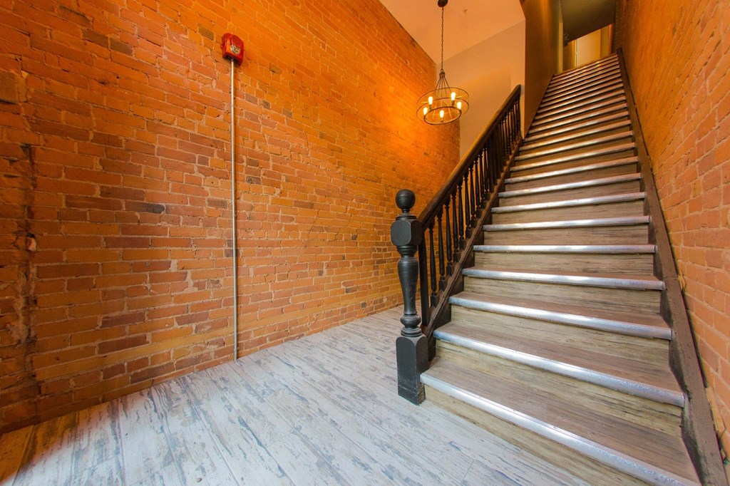 the staircase leading up to the second floor of a building with brick walls and wood