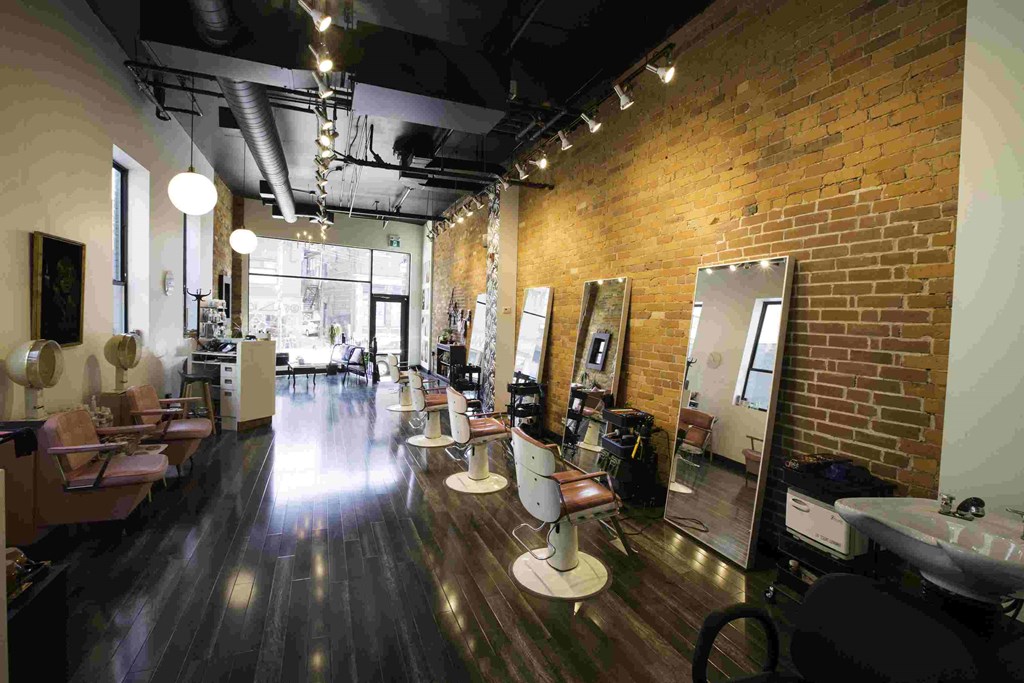 a beauty salon with a wood floor and brick walls