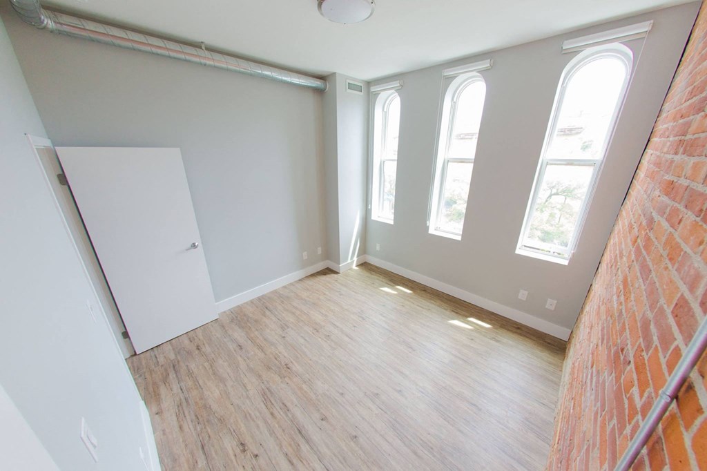 an empty room with a wood floor and windows