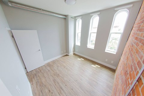 an empty room with a wood floor and windows