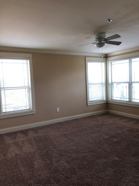 a living room with a ceiling fan and two windows