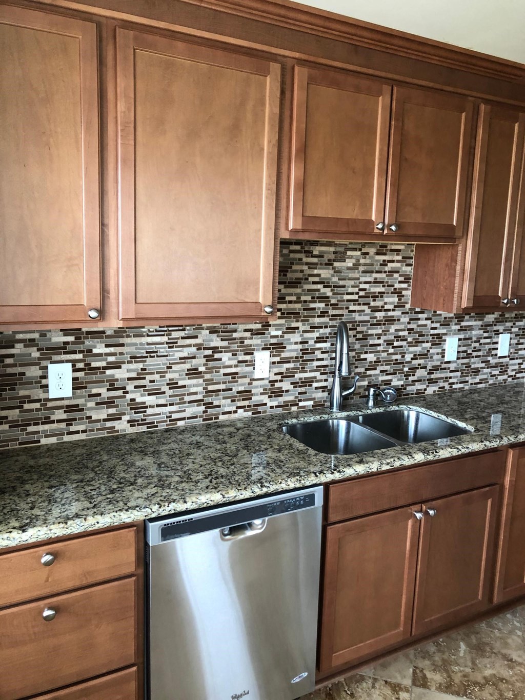 a kitchen with wooden cabinets and a stainless steel sink