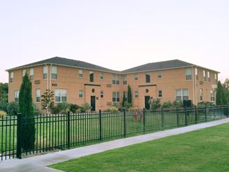 a large brick apartment building behind a black fence
