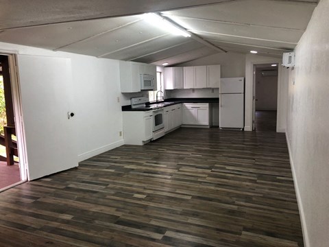 an empty kitchen with a wooden floor and white cabinets
