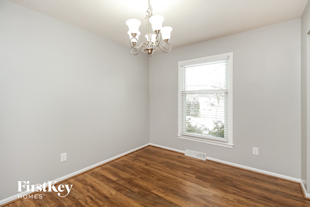 a bedroom with a window and wooden floors and a chandelier