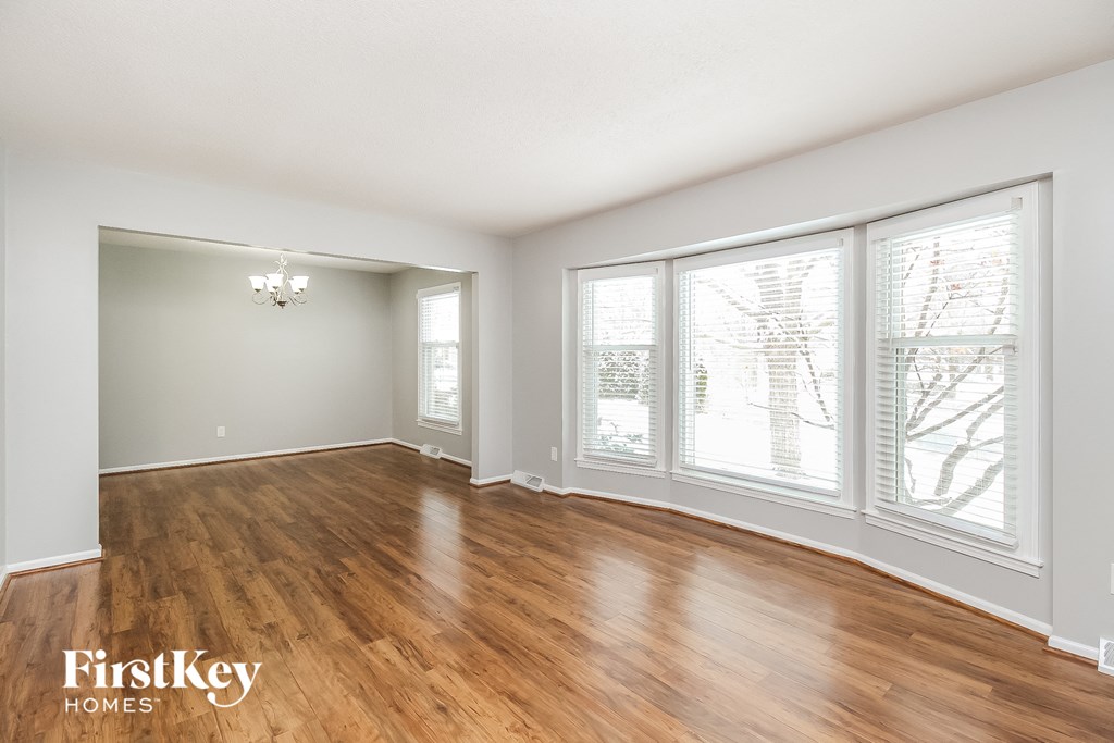 an empty living room with wood floors and large windows