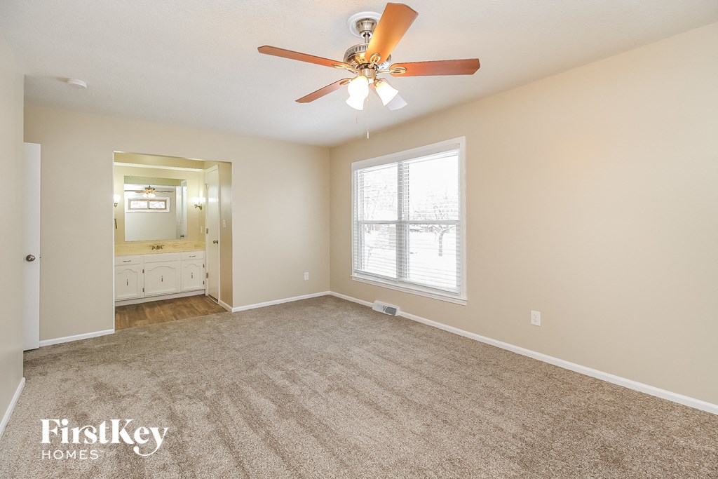 an empty living room with a ceiling fan and a large window