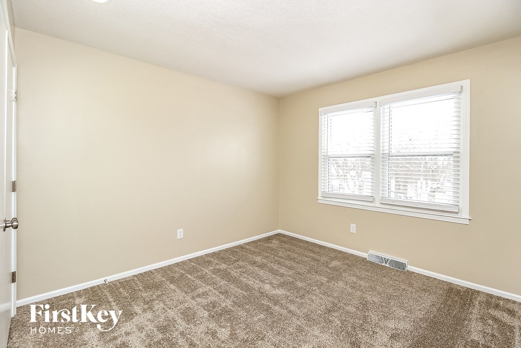 a bedroom with a carpeted floor and a window