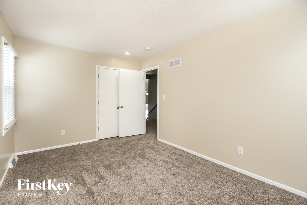 a living room with carpet and a door to a closet
