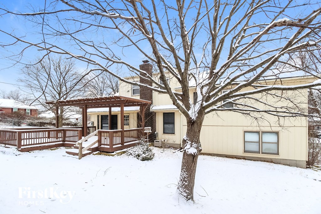 a home with a deck and a tree in the snow