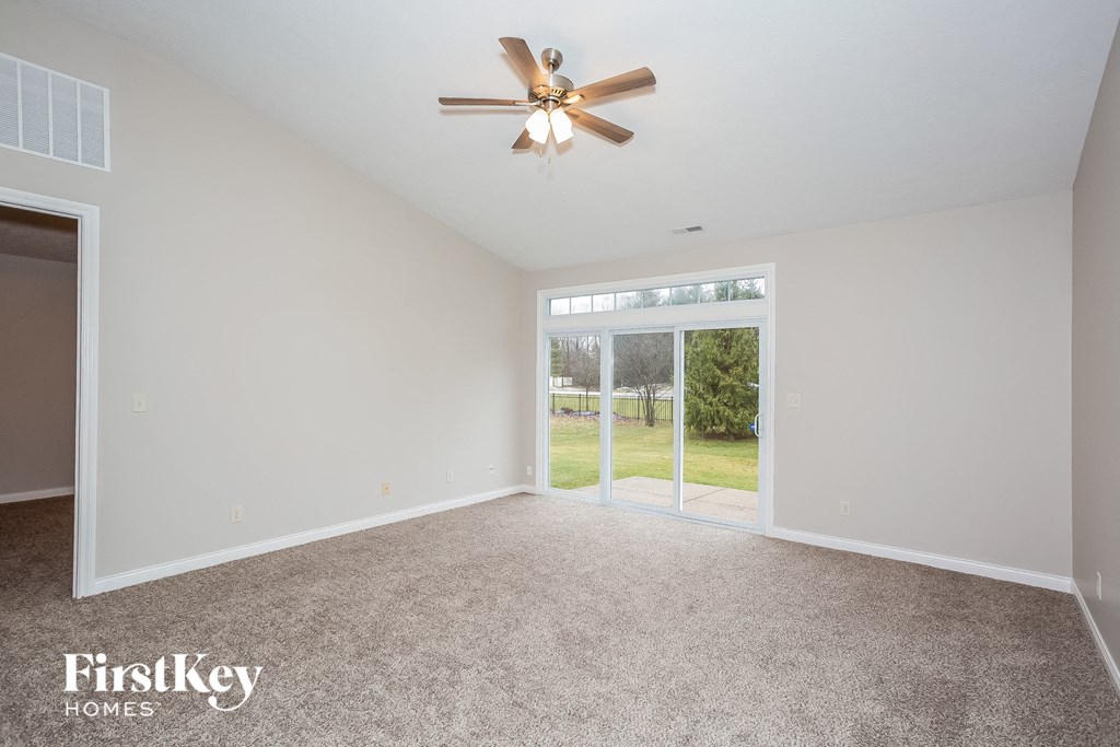 an empty living room with a ceiling fan and a door to a yard