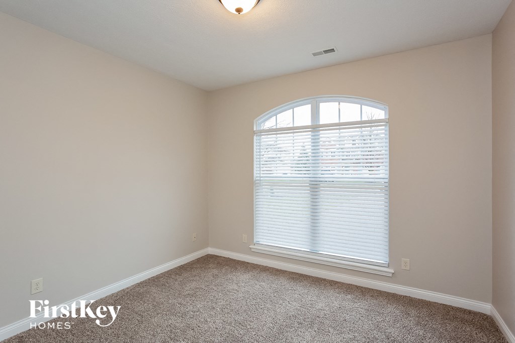 the second bedroom has a large window and carpeted flooring