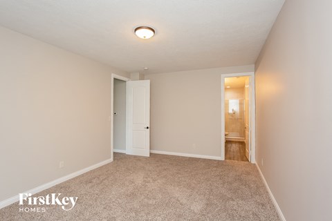 a spacious living room with carpet and a door to the bathroom