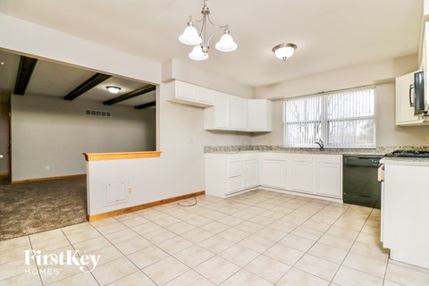 A kitchen with white cabinets and a tiled floor.