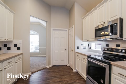 a kitchen with white cabinets and black appliances and a white door