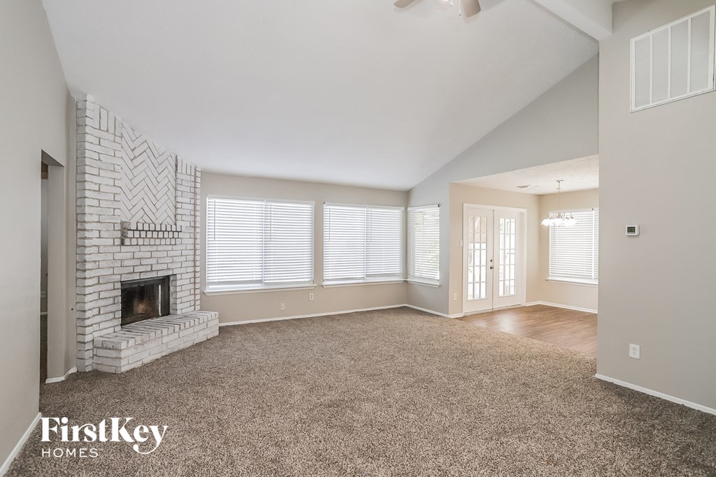 a living room with a brick fireplace and a carpeted floor