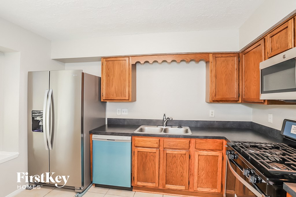 a kitchen with wooden cabinets and stainless steel appliances and a refrigerator