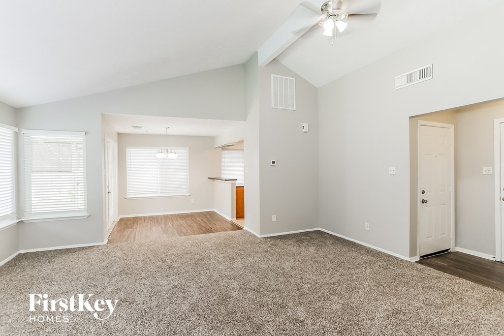 the living room and dining room with white walls and wood flooring