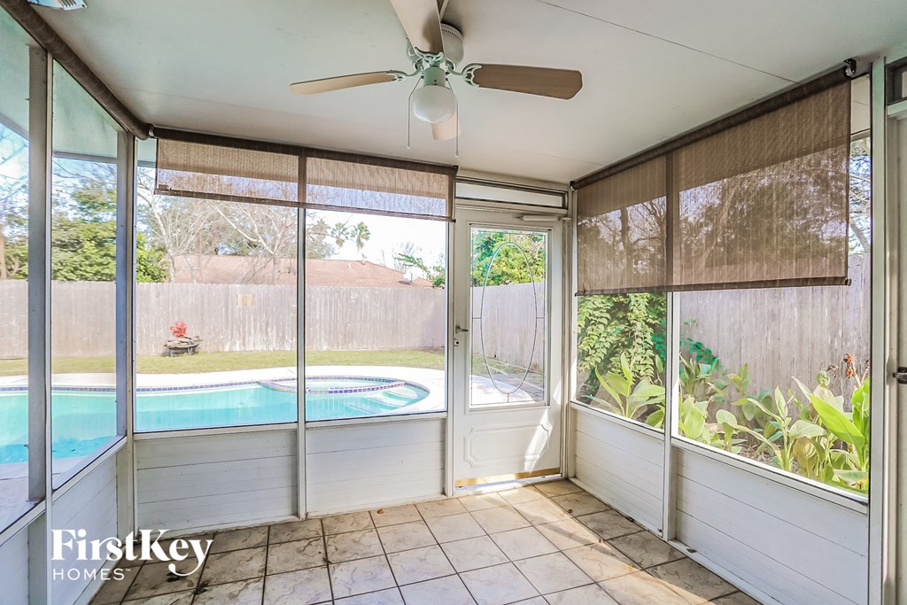 a screened in porch with a pool and a ceiling fan