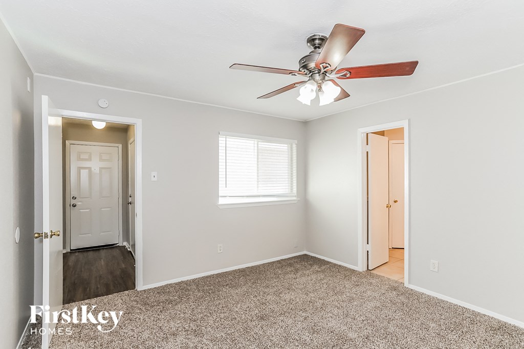 a bedroom with a ceiling fan and a door to a hallway