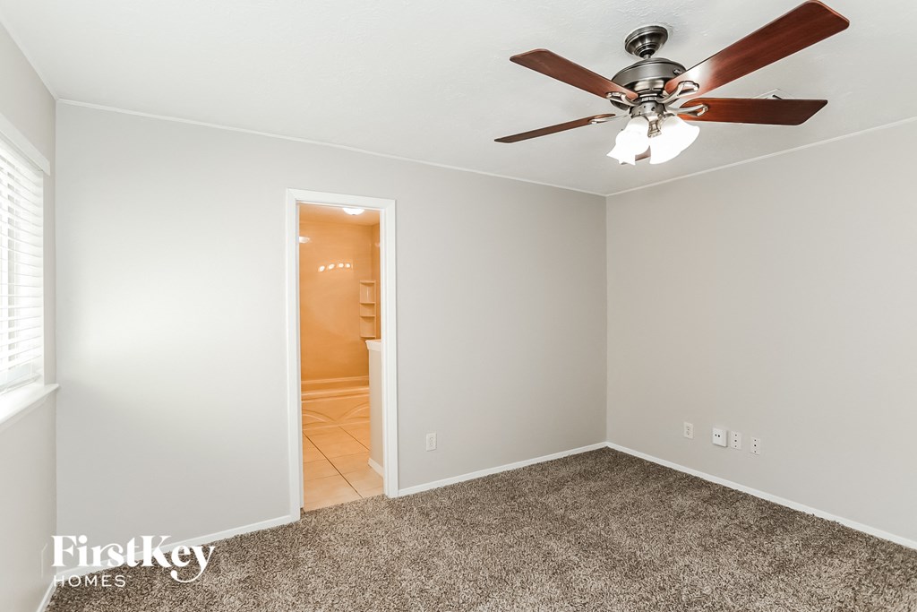 a bedroom with a ceiling fan and a door to a bathroom