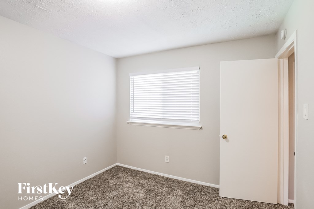 a bedroom with carpet and a window and a door