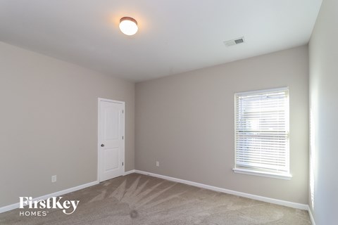 a bedroom with a white door and a window and a carpeted floor